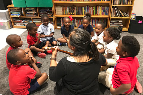 Children in circle singing with teacher