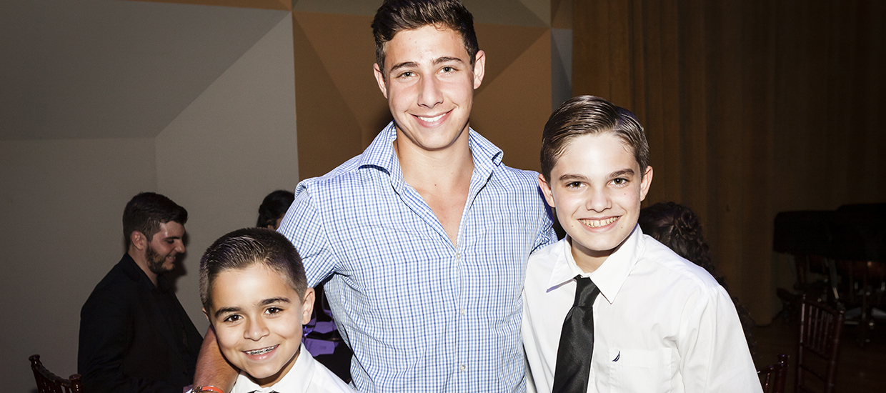 A man in a blue dress shirt poses with two kids at an event
